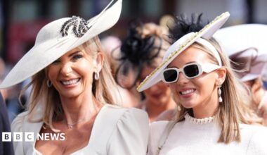 Two women wearing white dresses and hats arrive at Aintree