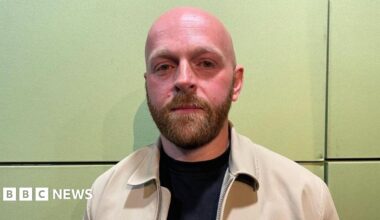 A view of the  Morrisons store, a brick and glass structure, with shelves of plans in front of the entrance