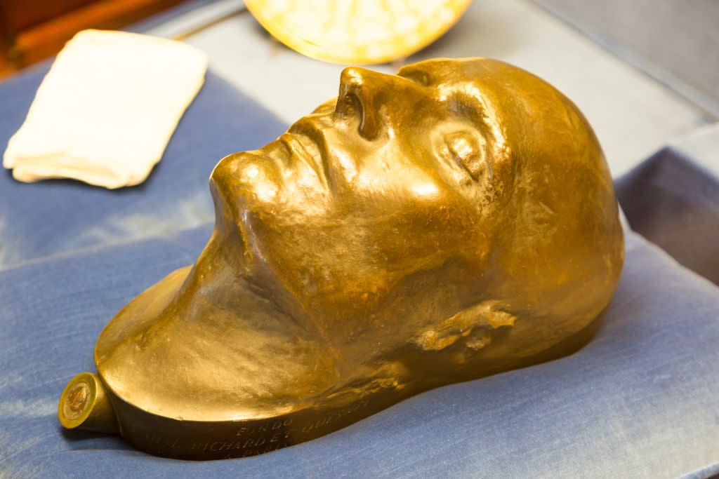 Bronze death mask on display, sculpted in a serene facial expression