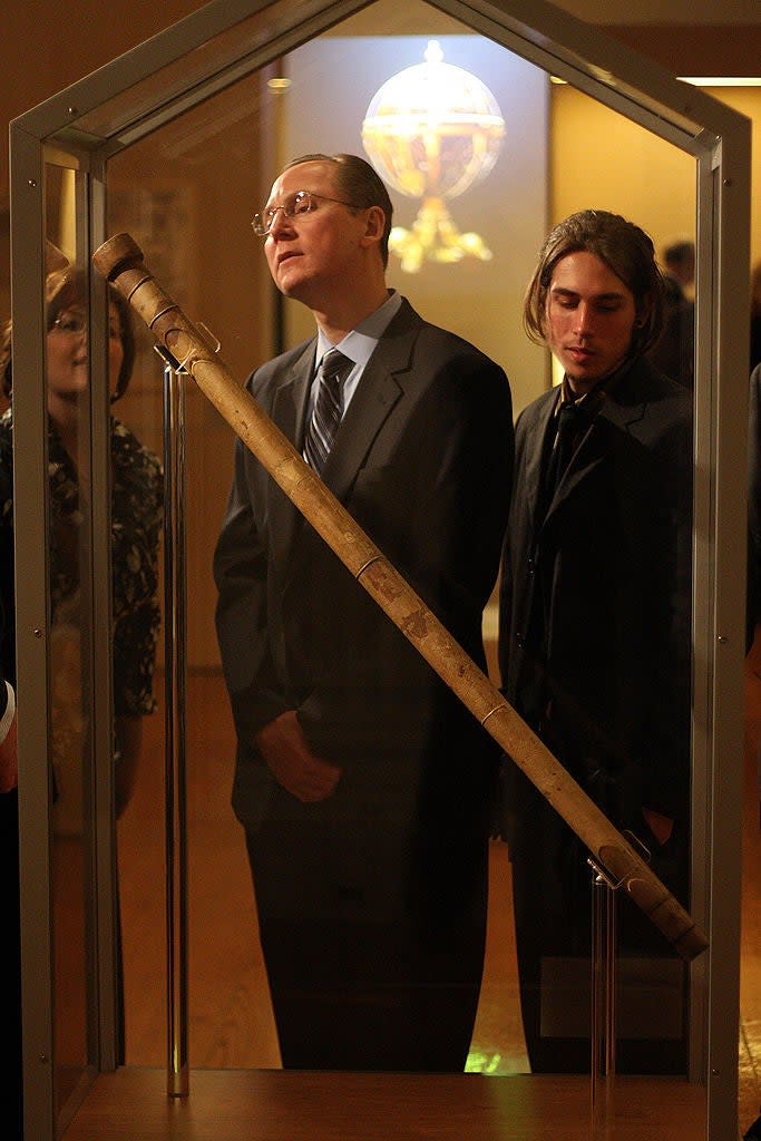 Two people observe a historical artifact in a museum display case