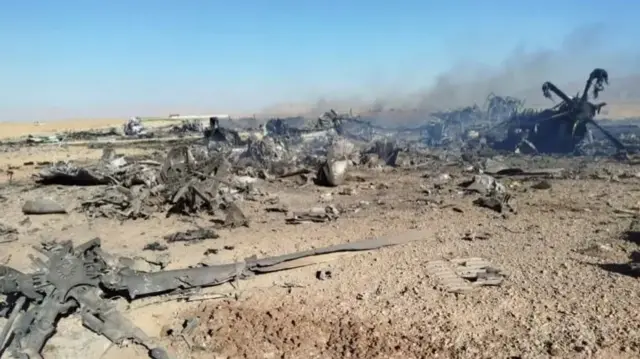 A photograph showing charred debris smoking