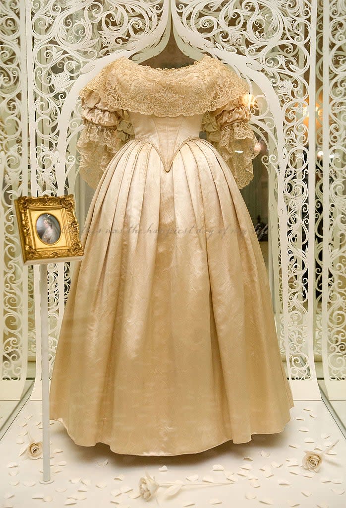 Elegant vintage dress with lace details displayed in an ornate setting, accompanied by a small framed portrait