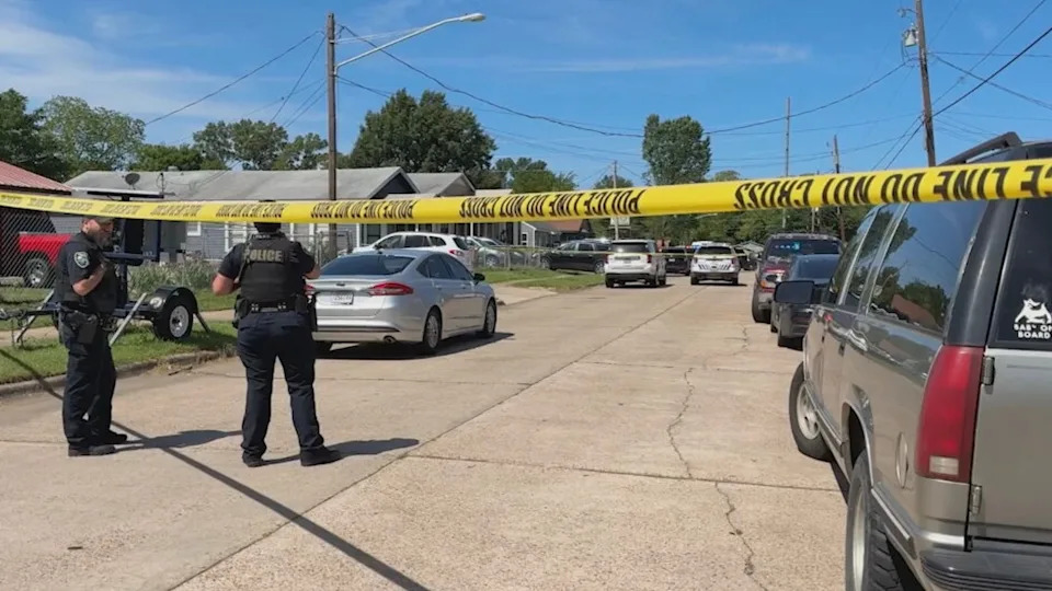 KTSB - PHOTO: Shreveport police officers stand behind crime scene tape as detectives collect evidence at two homes nearby where a suspect allegedly fatally shot eight children, April 19, 2026.