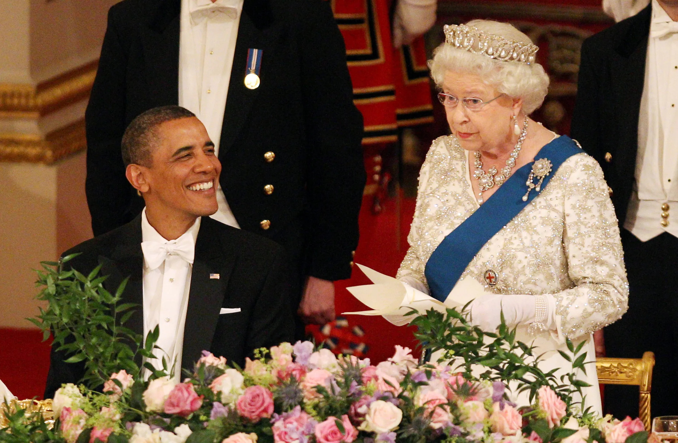 Queen Elizabeth II giving a speech at a state banquet at Buckingham Palace, with US President Barack Obama smiling beside her.