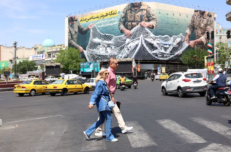 epa12918541 Iranians walk past a huge billboard carrying a sentence reading in Persian 'The Strait of Hormuz remains closed' at Enghelab Square in Tehran, Iran, 28 April 2026. US President Donald Trump announced that a ceasefire between the US and Iran has been extended. EPA/ABEDIN TAHERKENAREH
