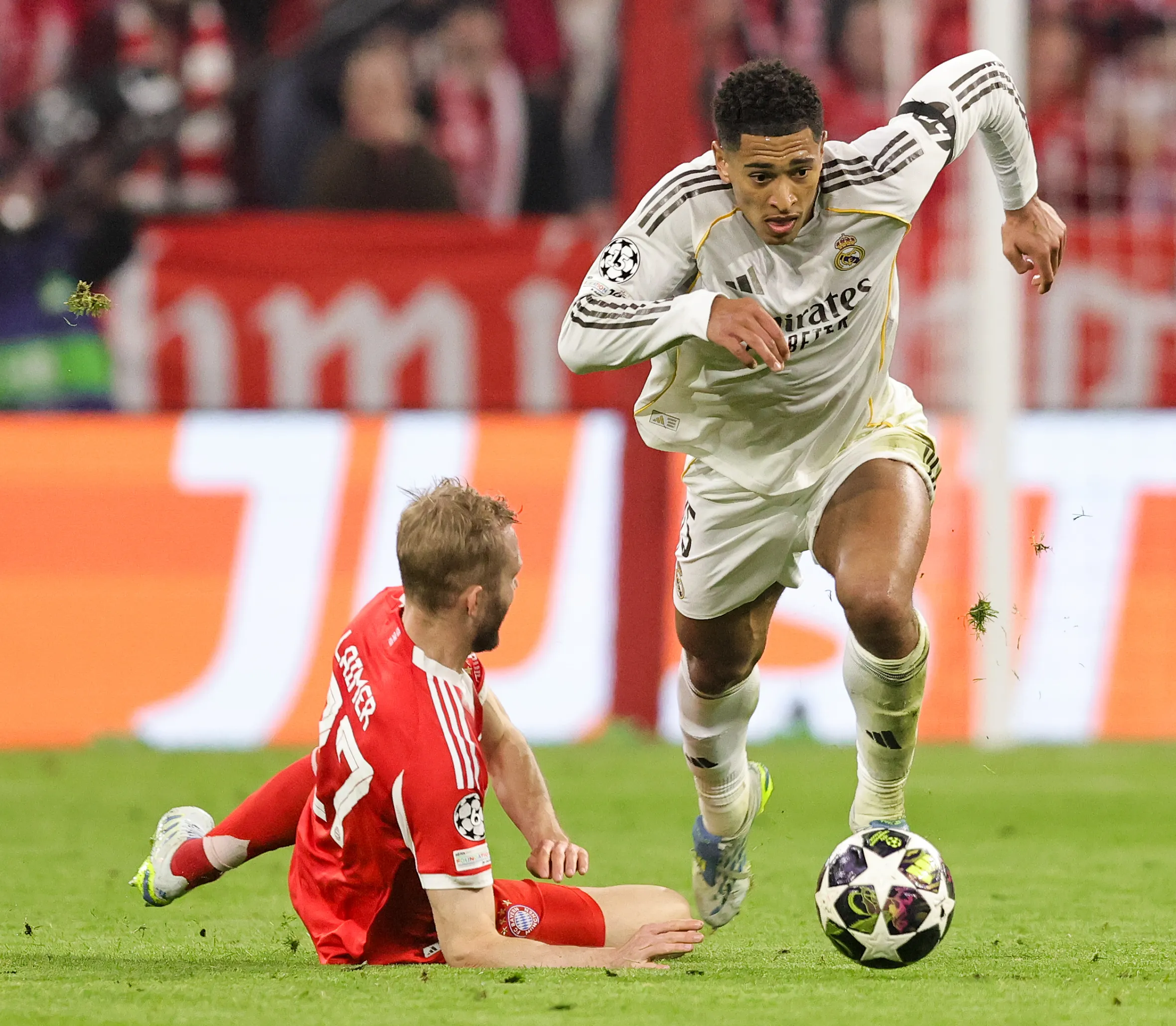 Jude Bellingham of Real Madrid playing the ball against a Bayern Munich player during a UEFA Champions League match.