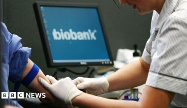 Nurse taking blood from person as biobank logo appears on screen in background.