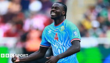 DR Congo defender Axel Tuanzebe celebrates a goal for his country against Jamaica in their World Cup play-off win. He is seen from waist up clenching his right fist at waist level while tilting his head up slightly, with eyes closed and a look of delight on his face