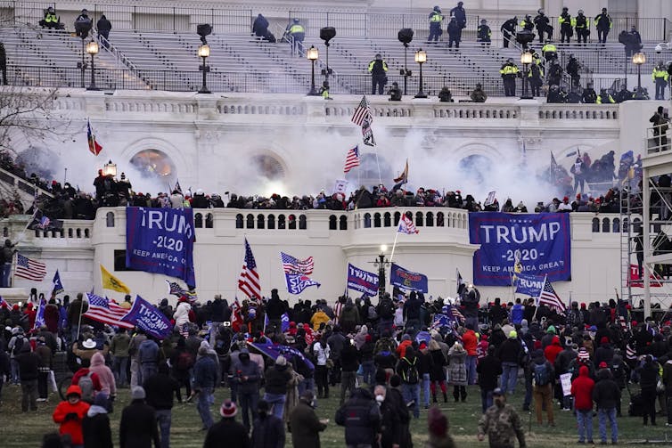 Trump 2020 signs hang in front of the Capitol Building amid a riot.