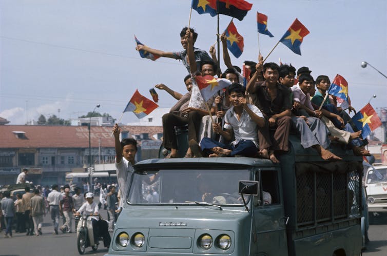 People hold aloft flags on top of a bus.
