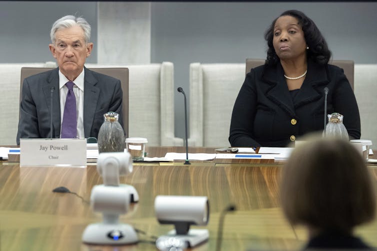 a white man and a Black woman sit at chairs at a table
