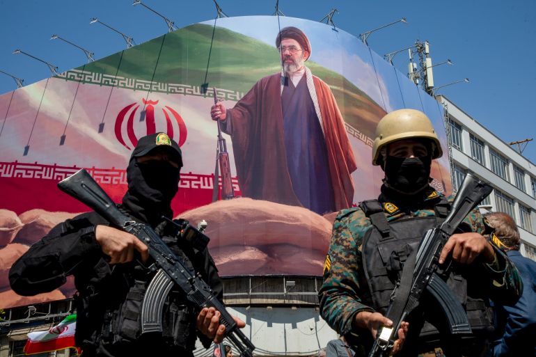 TEHRAN, IRAN - APRIL 9: Members of the Iranian security forces stand guard under a large portrait of Iran's new Supreme Leader, Mojtaba Khamenei, during a memorial to mark the 40th day since his father, Ali Ayatollah Khamenei, was killed in US-Israeli joint strikes, on April 9, 2026 in Tehran, Iran. On April 8 President Donald Trump announced a two-week ceasefire between the US and Iran, conditional on shipping being allowed to resume through the Strait of Hormuz. (Photo by Majid Saeedi/Getty Images)