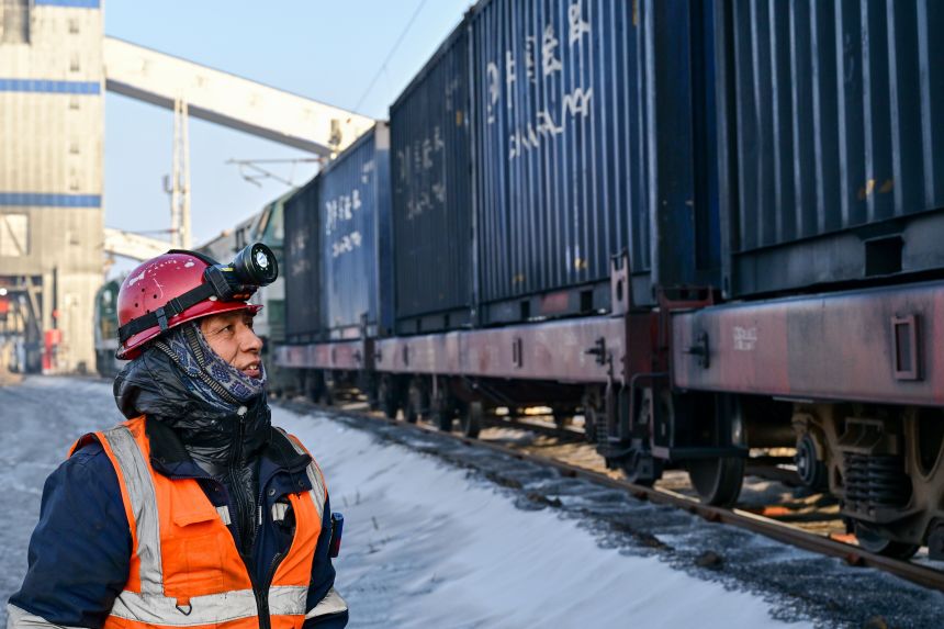 A staff worker inspects a freight train at a loading station at the Zhundong open-pit coal mine in northwest China's Xinjiang region last year.