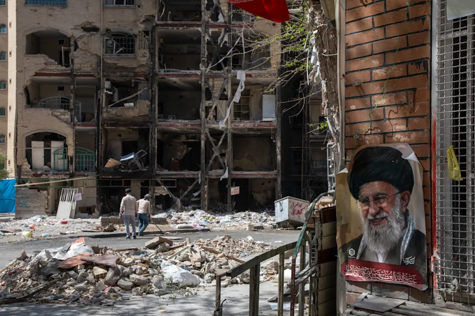 Men walk past the remnants of a building in Tehran on April 14.