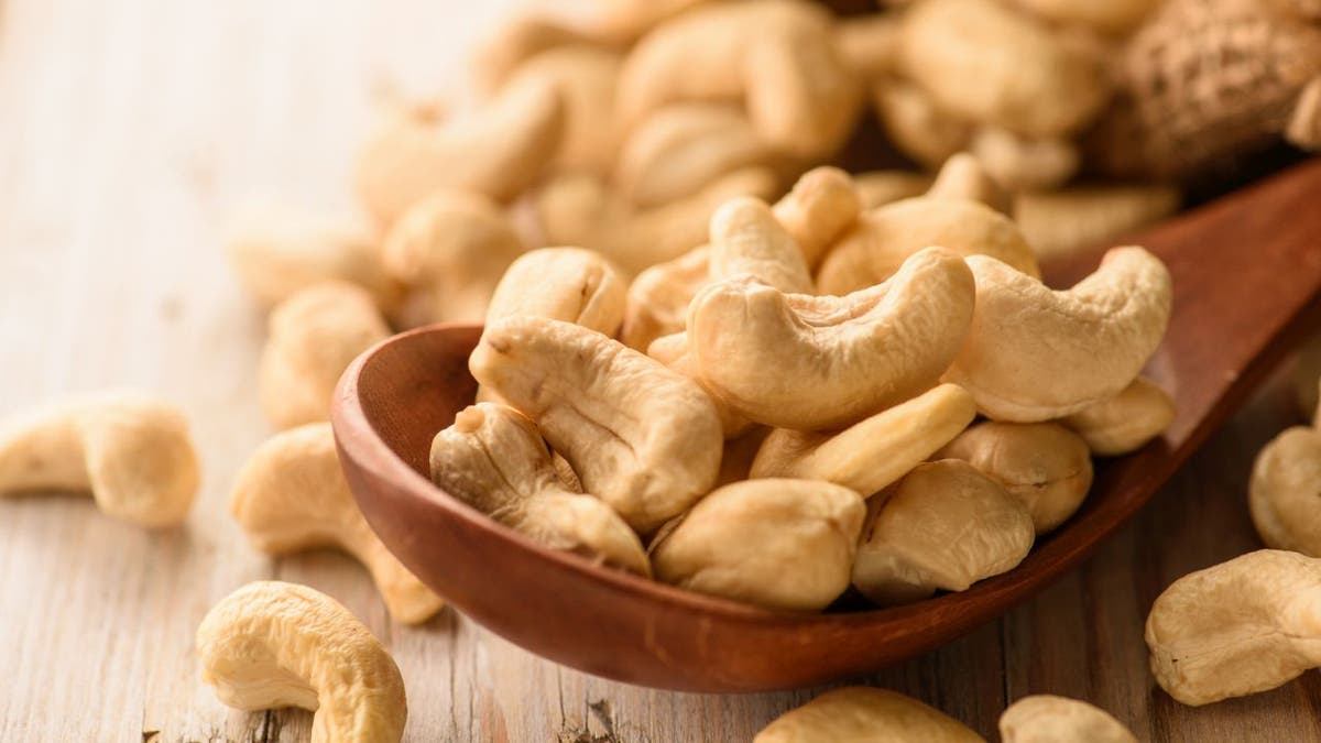 Close up of cashew nuts in a wooden spoon on a wooden table