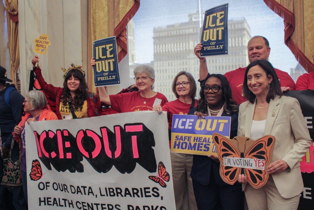 Kendra Brooks and Rue Landau pose with activists holding up signs saying 'ICE Out'