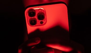 a person holding an iPhone facing the camera in a red backdrop