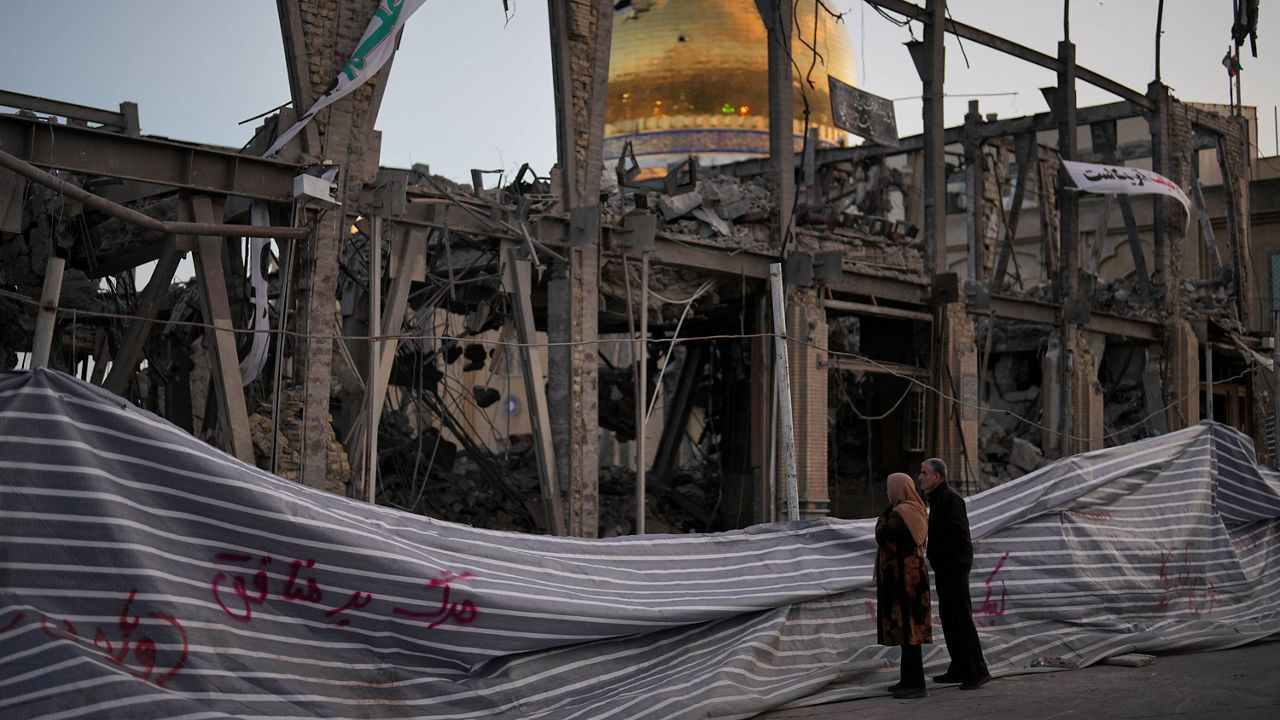 Pedestrians look at a destroyed building within the Grand Hosseiniyeh, with the mosque visible in the background, which officials at the site say was hit by U.S.-Israeli airstrikes Tuesday, in Zanjan, Iran, Saturday, April 4, 2026. (AP Photo/Francisco Seco)