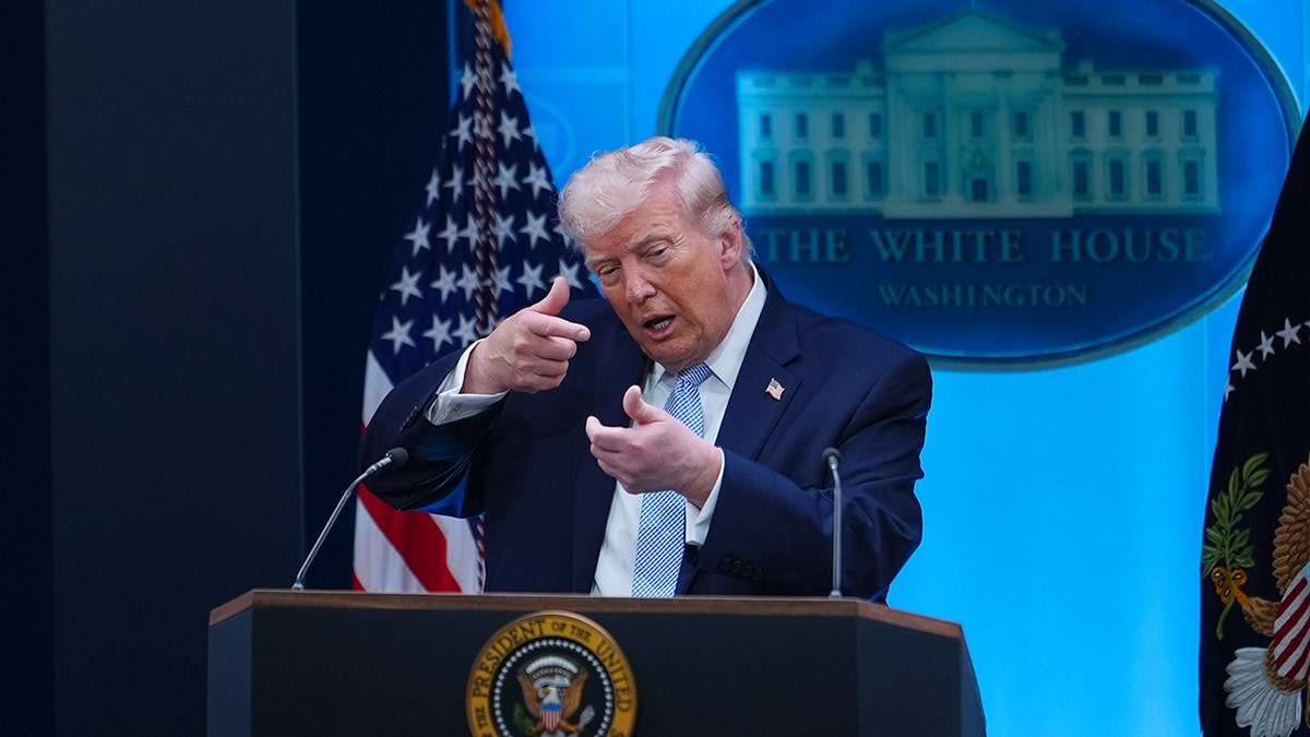 Donald Trump gesturing with his hands as if aiming a long firearm.