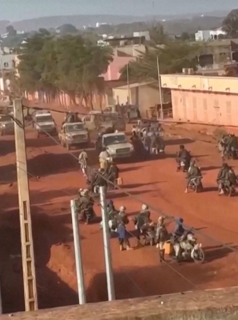Vehicles move through a group of armed men on motorbikes standing on a street in Kati, near the capital city Bamako, Mali, in this screengrab obtained from a social media video released on April 25, 2026. Social Media/Reuters TV via REUTERS. NO RESALES. NO ARCHIVES. Verfication lines: Buildings, road layout, foliage and hills match satellite imagery. Date could not be verified, however, Mali's army said unidentified groups attacked several positions in the capital and elsewhere in the country on April 25. No older versions of the video could be found posted online before April 25.