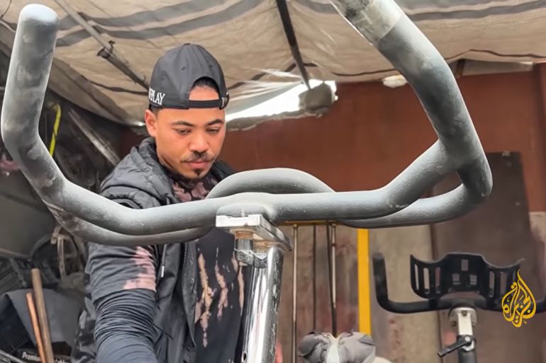 Fitness coach and gym owner Muhannad Qasem was forced to sell the few pieces of equipment he salvaged from the rubble on the street to feed his family. [Screengrab/Al Jazeera]