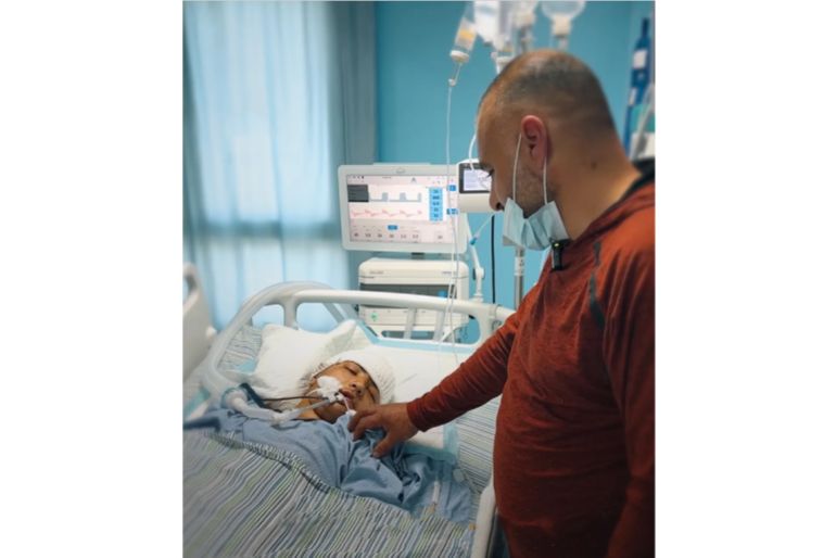 13-year-old Mohammad Saber al-Sheikh remains in critical condition in Ramallah, with his father, Saber, watching over him after he was shot while playing football.