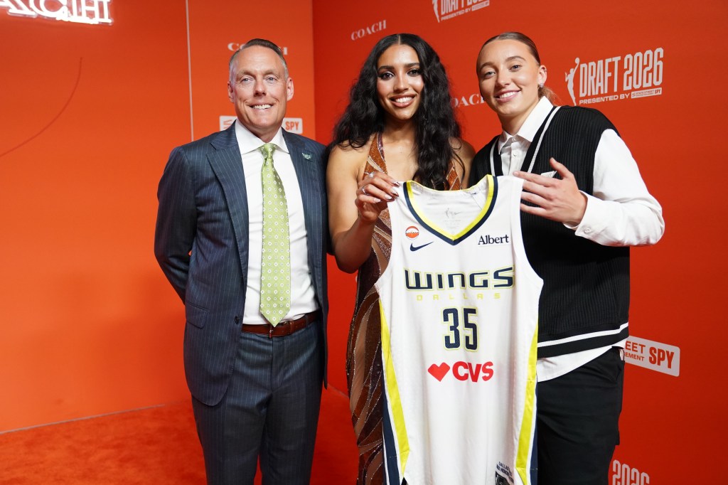 Greg Bibb, Azzi Fudd, and Paige Bueckers holding a Dallas Wings jersey during the 2026 WNBA Draft.
