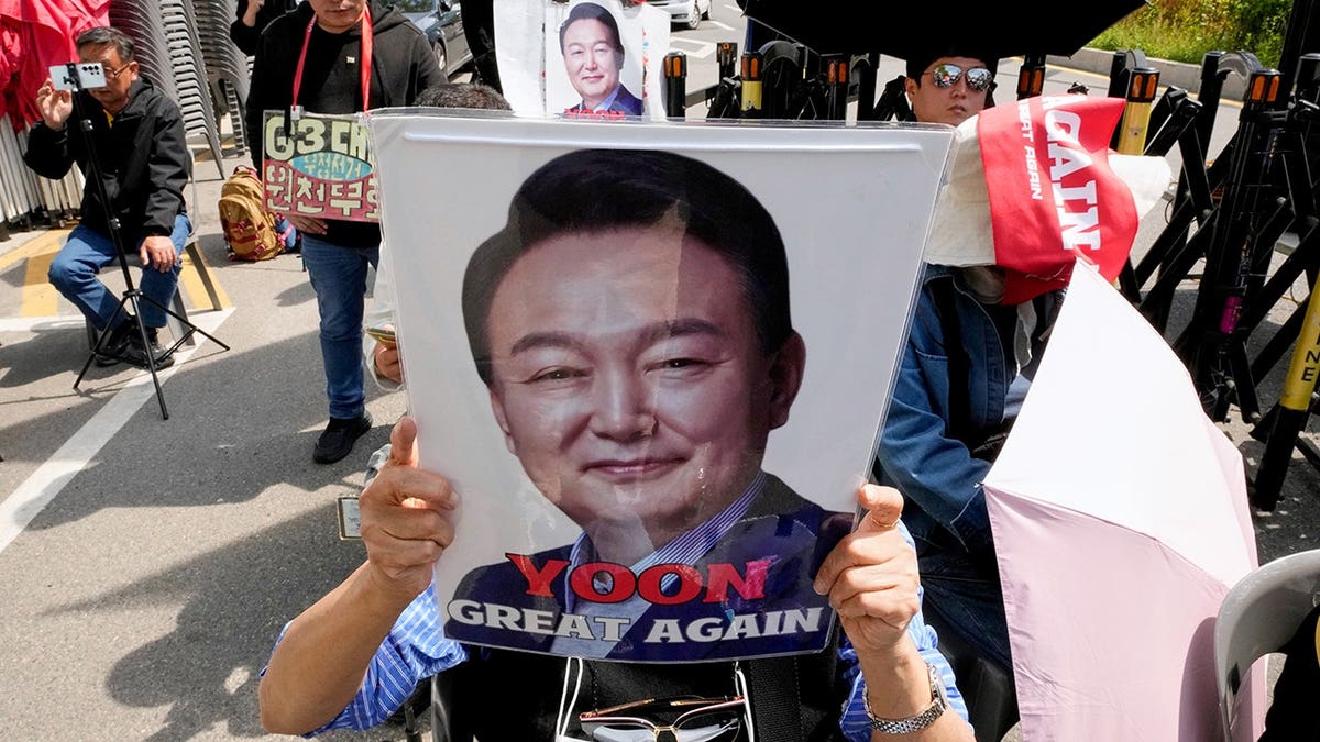 A supporter of former South Korean President Yoon Suk Yeol holding up his portrait outside Seoul High Court