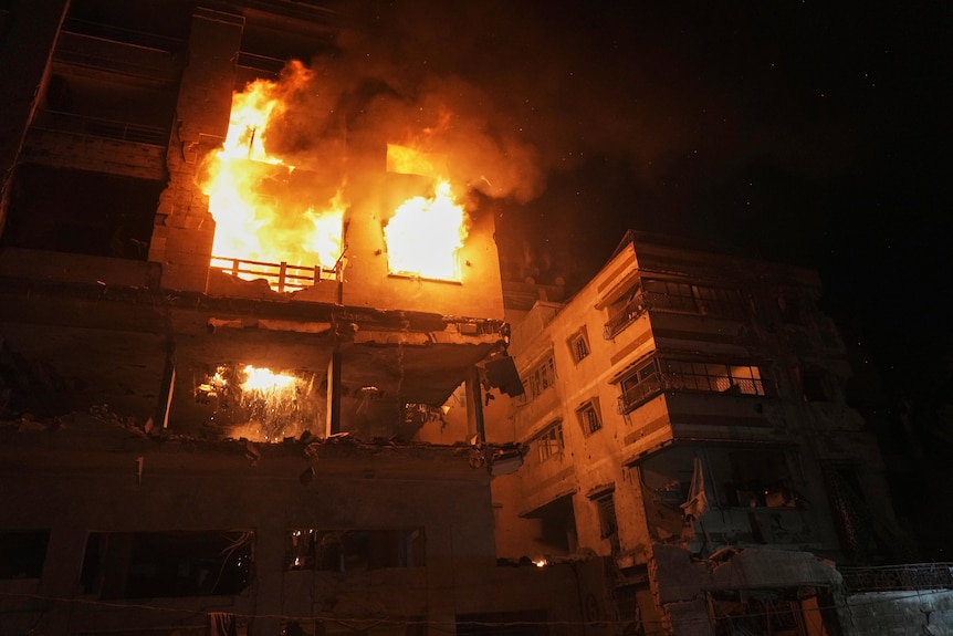 Flames engulf a residential building on the second floor, with flames coming through four windows.