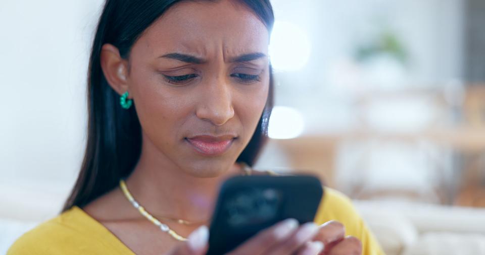 Person looking at phone with a frustrating expression.