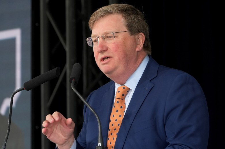 Tate Reeves, in a blue suit and gold tie, speaks at an Amazon press conference