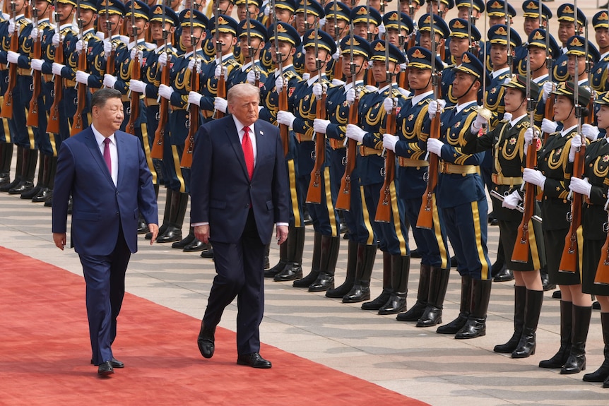 US President Donald Trump walks with China's President Xi Jinping in front of Chinese guards.