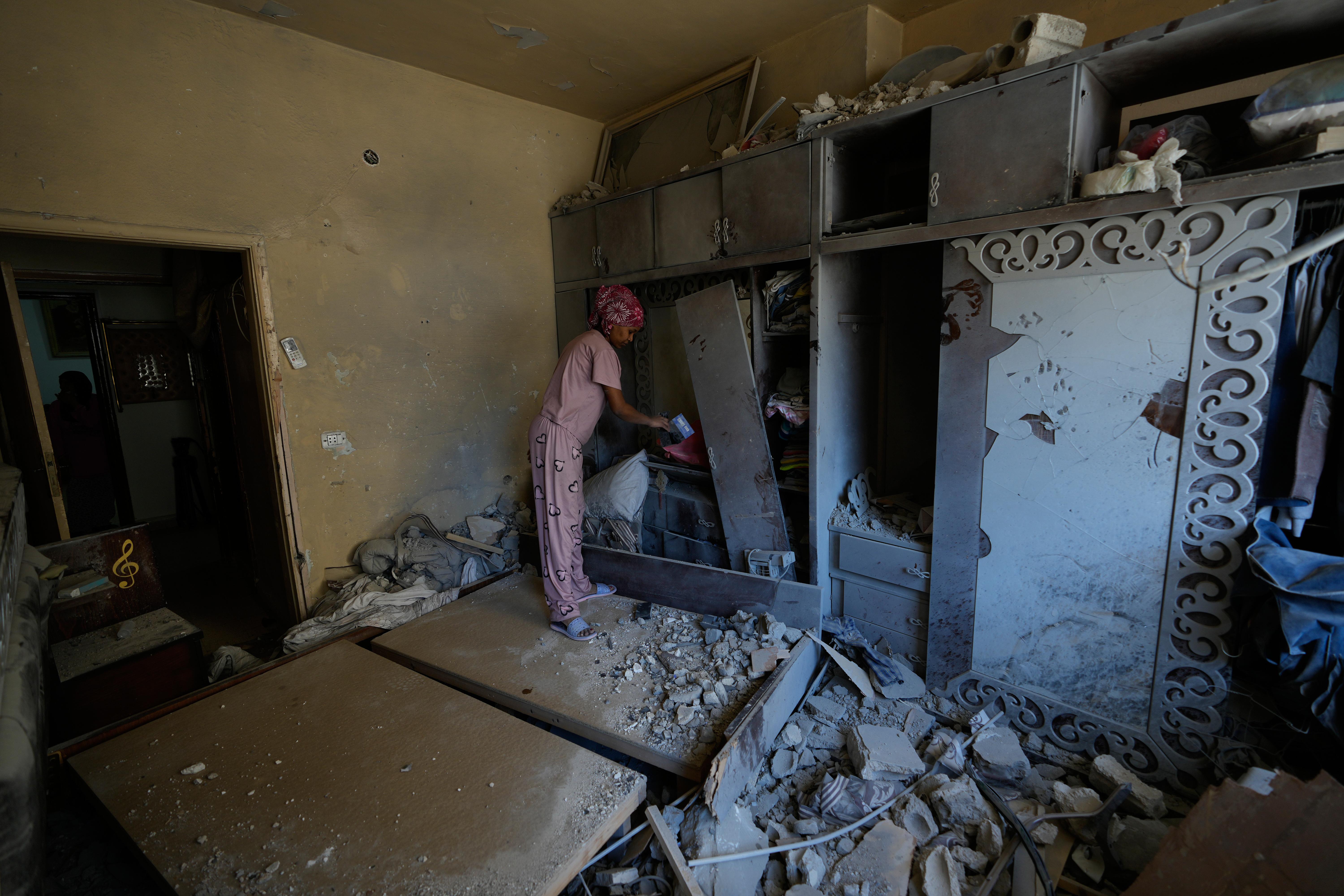 A domestic worker cleans a damaged bedroom