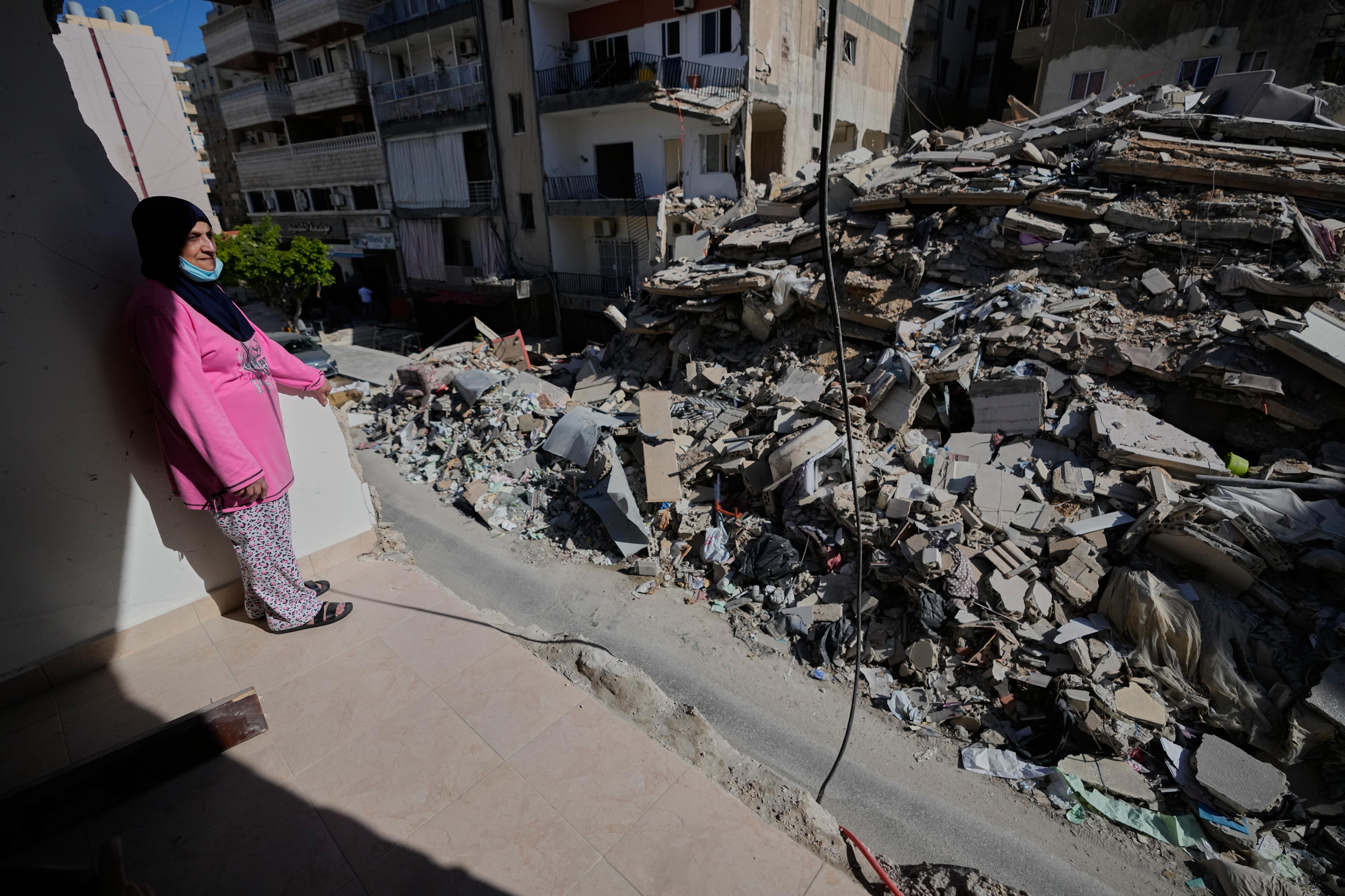 Em Ali Khodor, 75, looks through her damaged apartment into a destroyed building