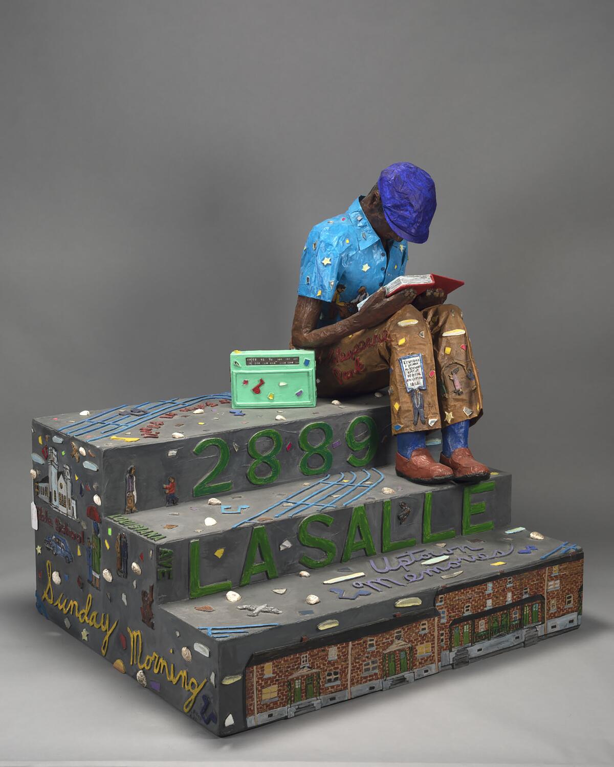 Painted papier-mâché of a young man sitting on steps reading a book and listening to a radio.