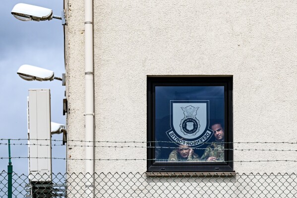 U.S. Air Force Airmen watch from a window as U.S. Vice President JD Vance disembarks Air Force Two upon his arrival at Ramstein Air Base, Germany, Thursday, April 24, 2025. (Kenny Holston/Pool Photo via AP)
