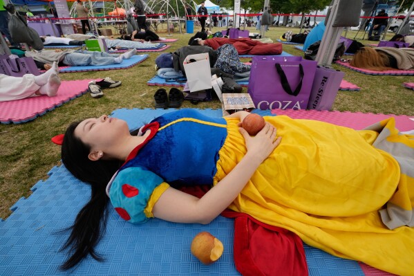 A participant dressed as Snow White takes a nap during the 2026 Hangang Nap Competition at Yeouido Hangang Park in Seoul, South Korea, Saturday, May 2, 2026. (AP Photo/Ahn Young-joon)