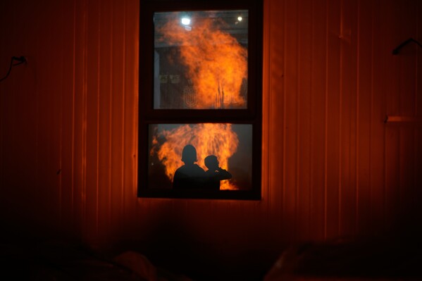 Ultra-Orthodox Jewish boys are reflected in a window as they stand around a bonfire during Lag BaOmer, a holiday traditionally celebrated with bonfires, music, and gatherings, in Jerusalem, Monday, May 4, 2026. (AP Photo/Ohad Zwigenberg)