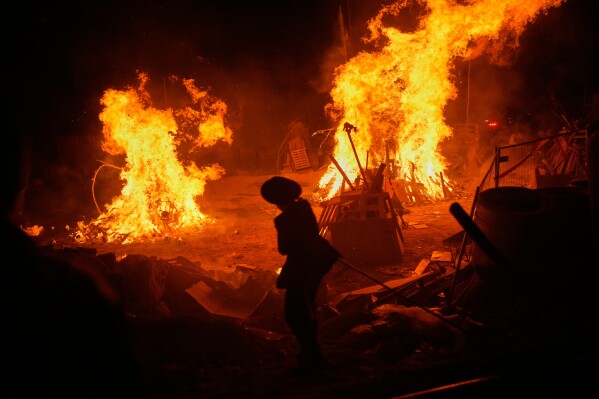 An ultra-Orthodox Jewish youth stands next to bonfires during Lag BaOmer, a holiday traditionally celebrated with bonfires, music, and gatherings, in Jerusalem, Monday, May 4, 2026. (AP Photo/Ohad Zwigenberg)