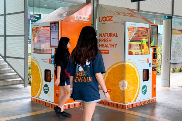 People walks past IJooz vending machines in Singapore, Thursday, April 30, 2026. (AP Photo/David Hu)