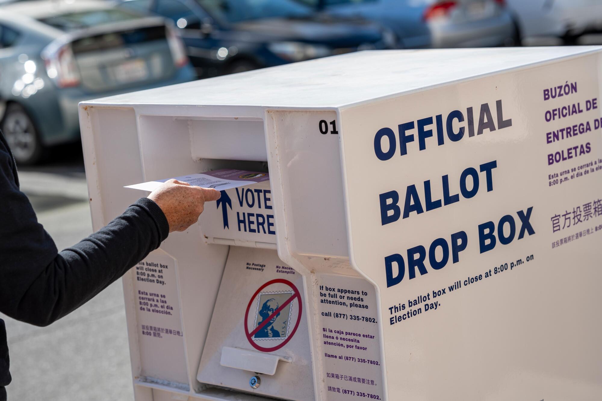 A voter submitting their ballot at an official ballot drop box.