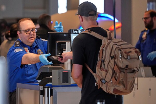 A Transportation Security Administration worker hands a passport back to a traveler at a TSA checkpoint at Pittsburgh International Airport in Imperial, Pa., March 23, 2026. (AP Photo/Gene J. Puskar, File)