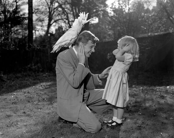 Three year old Susan and her father David Attenborough pose for a photo with a sulphur-crested cockatoo Georgie, Dec. 7, 1957. (PA via AP)