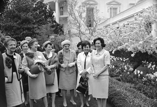 First lady Lady Bird Johnson, right, stands near tulips and a flowering crabapple tree with leaders of a "Let's Beautify America" campaign while they call on her at the White House in Washington, April 28, 1965. (AP Photo/John Rous, File)