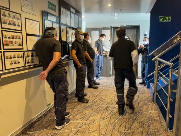 Crew members of the hantavirus-stricken cruise ship, MV Hondius, wait their turns for a first interview with epidemiologists, during the voyage to Spain's port of Tenerife, May 6, 2026. (AP Photo)