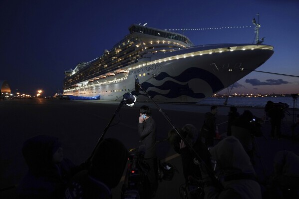 Journalists work near the quarantined Diamond Princess cruise ship sitting at the Yokohama Port on Feb. 10, 2020, Yokohama, Japan. (AP Photo/Eugene Hoshiko, File)