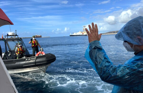 A passenger waves to the Guardia Civil officers as they are disembarked from the hantavirus-stricken cruise ship MV Hondius at the port of Granadilla in Tenerife, Canary Islands, Spain, Sunday, May 10, 2026. (AP Photo)