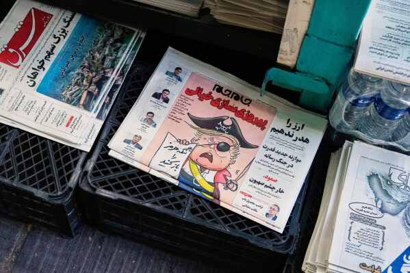 The front page of the Sunday May 10, 2026, edition of Iranian newspaper, Jamejam, is seen with a cartoon satirizing the U.S. President Donald Trump that asks: "Open the the Strait of Hormuz" on a news stand in northern Tehran, Iran, Sunday, May 10, 2026. (AP Photo/Vahid Salemi)
