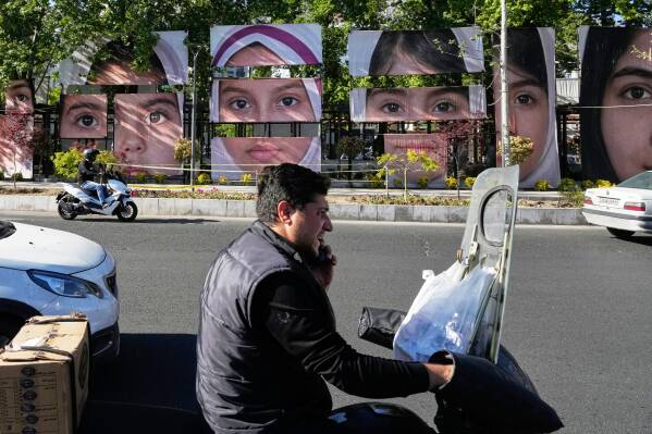 Vehicles drive past banners showing portraits of the school children who were killed during a strike on a school in southern town of Minab on Feb. 28, at Tajrish square in northern Tehran, Iran, Sunday, May 10, 2026. (AP Photo/Vahid Salemi)