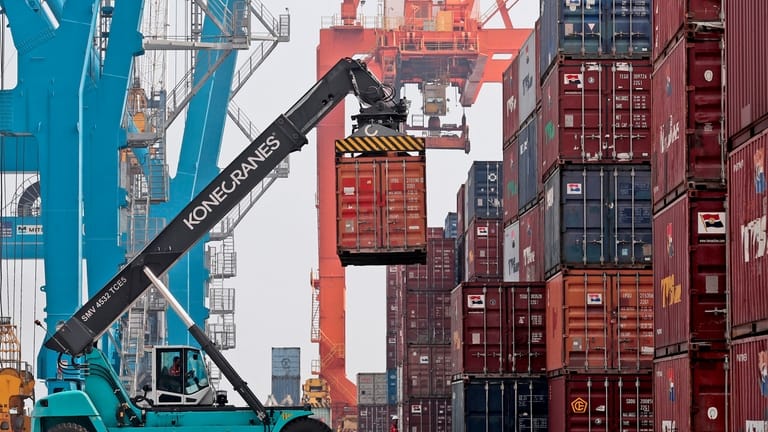 A stacker organizes containers at the terminal of Indonesia Port...